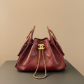 A red quilted leather handbag with gold-tone hardware, including a prominent interlocking CC logo on the front, resting on a dark surface with a Chanel box partially visible in the background.